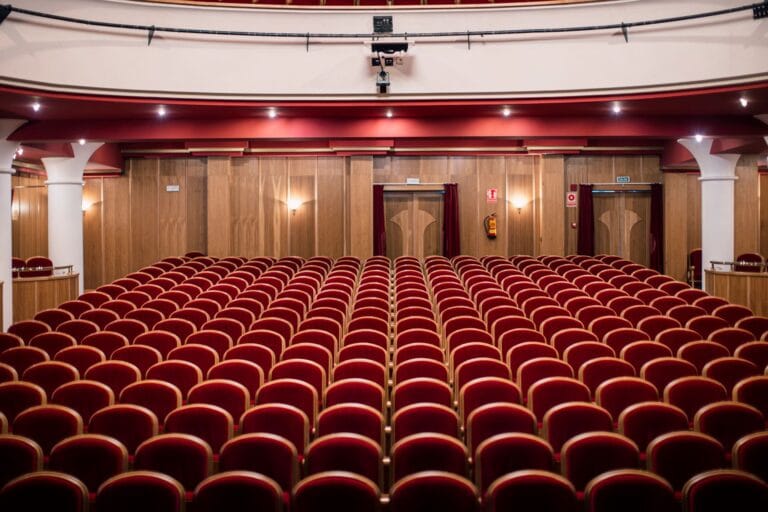 Pusta sala teatralna z czerwonymi fotelami i drewnianymi ś